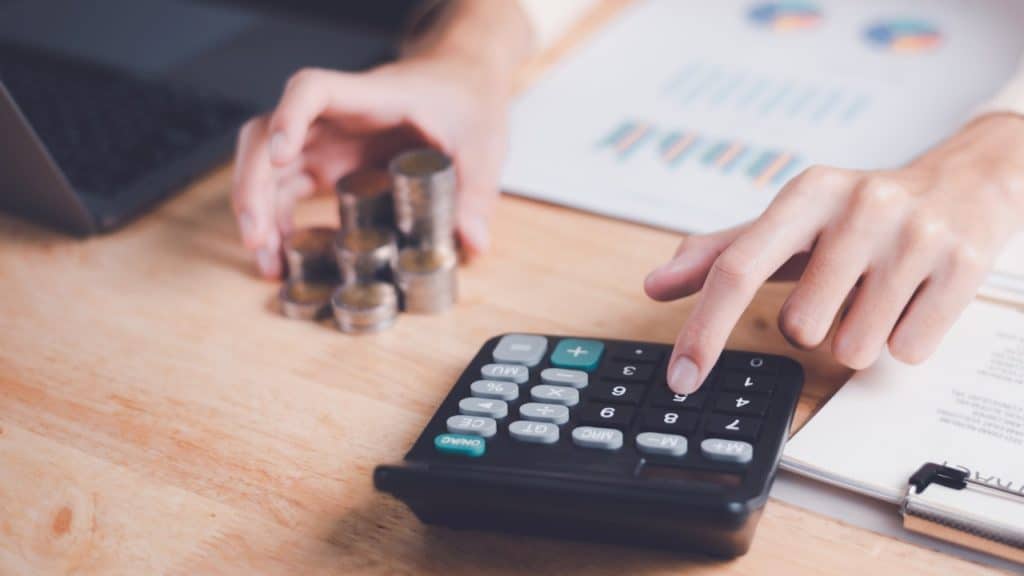 a person stacking up coins while using a calculator