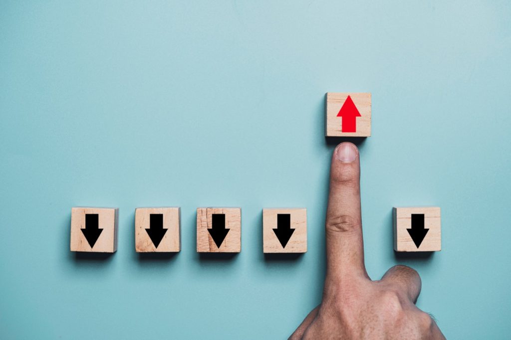 Finger pushing red up arrow which it opposite direction from black down arrow